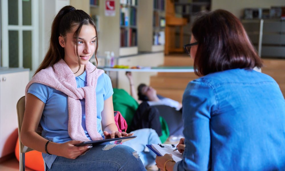 Woman school psychologist teacher talking and helping student, girl teenager